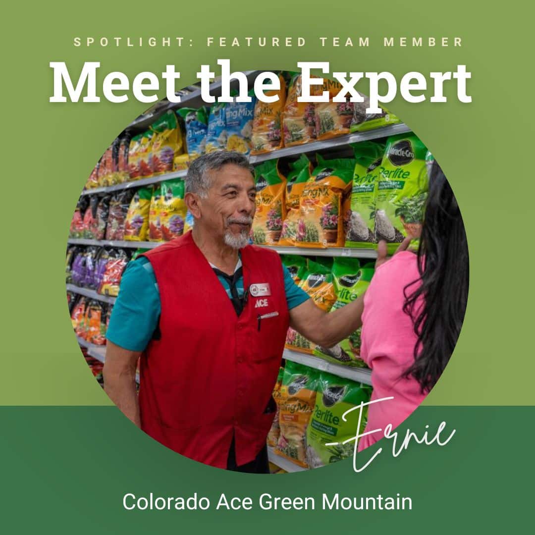 Ace Hardware team member Ernie in a red vest smiles while helping a customer in the garden supply aisle at Colorado Ace Green Mountain.