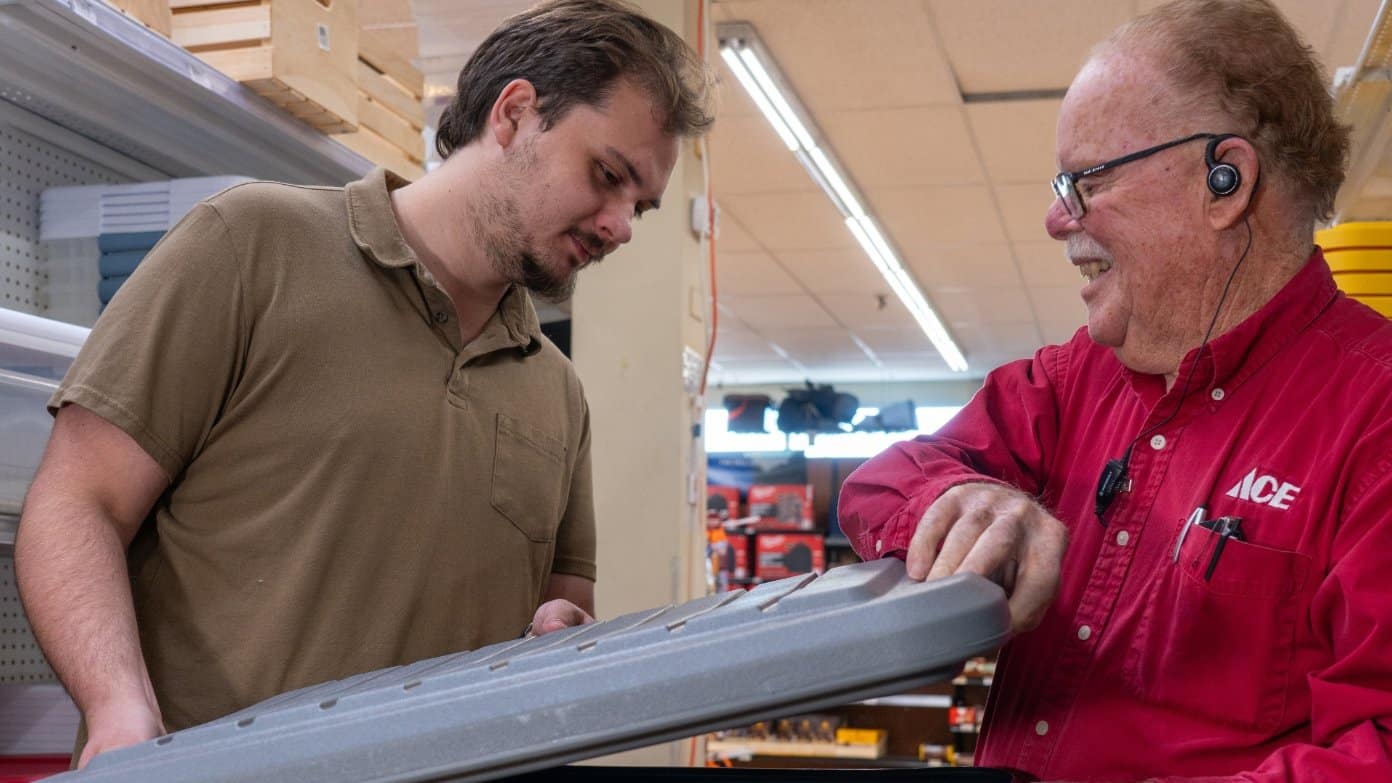 Colorado Ace Hardware team member holding a heavy-duty wall shelf inside the store
