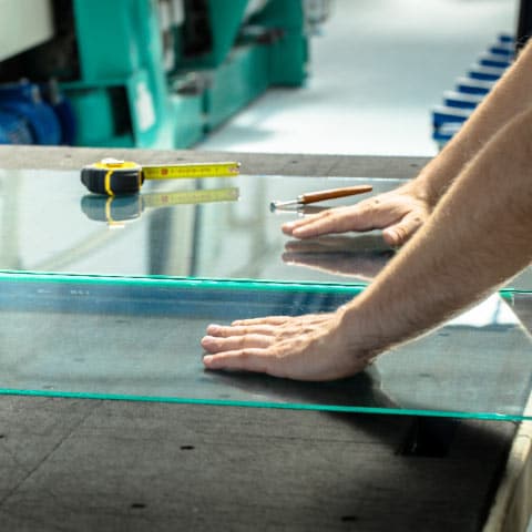 Worker professionally measuring and cutting pane of glass