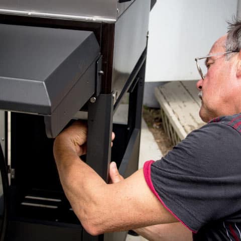 Man repairing a propane grill in customer's backyard