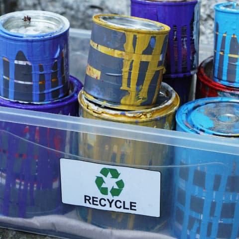 Plastic container filled with old cans of paint