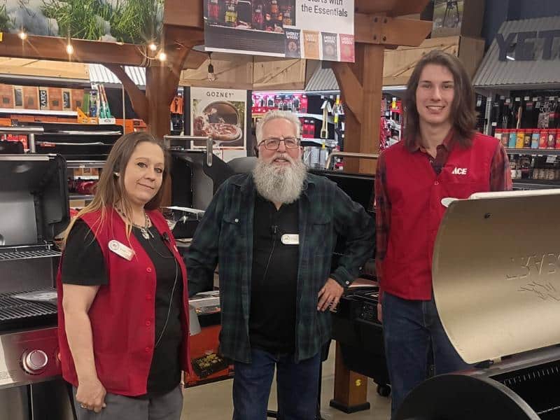 Ace Hardware team members standing by grill display inside store showroom