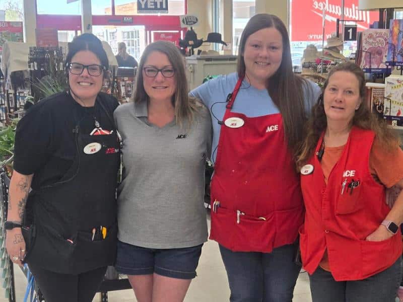 Ace Hardware employees smiling together near checkout area inside store