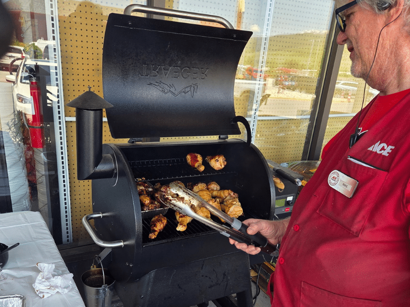 Ace Hardware employee grilling chicken on a Traeger smoker during in-store event