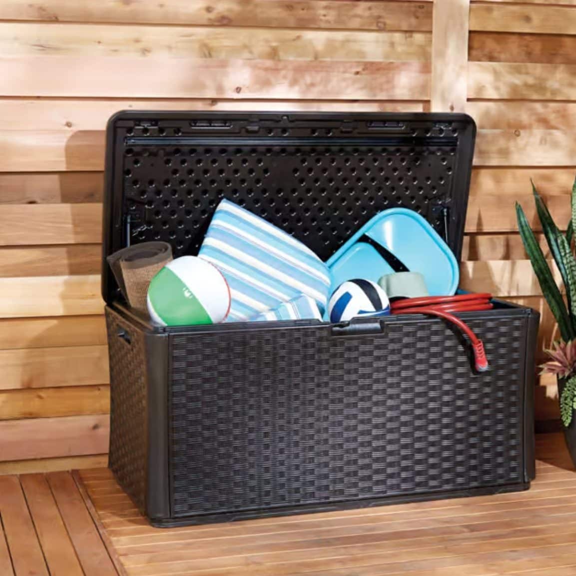 Outdoor deck storage box holding backyard toys and patio accessories