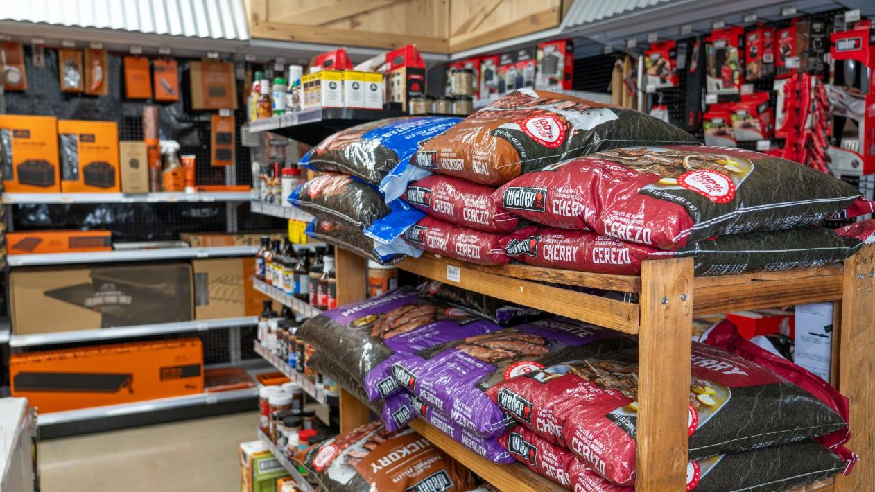 Selection of grilling pellets and smoking fuels displayed inside Colorado Ace Green Mountain.