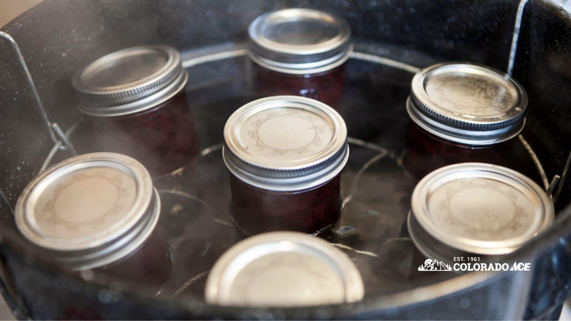 Sealed jars of preserves processing in a steaming water-bath canner