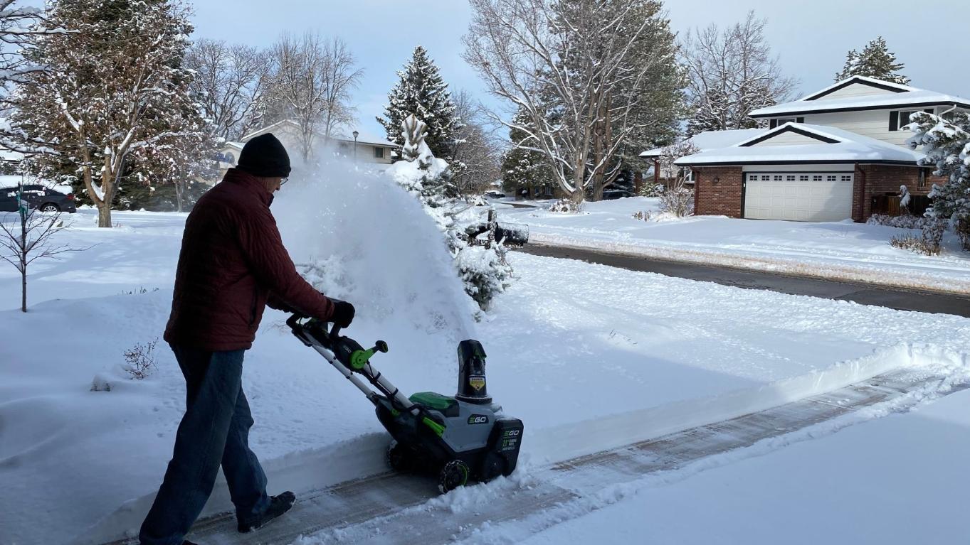 Person shoveling snow from a driveway during a Colorado winter storm
