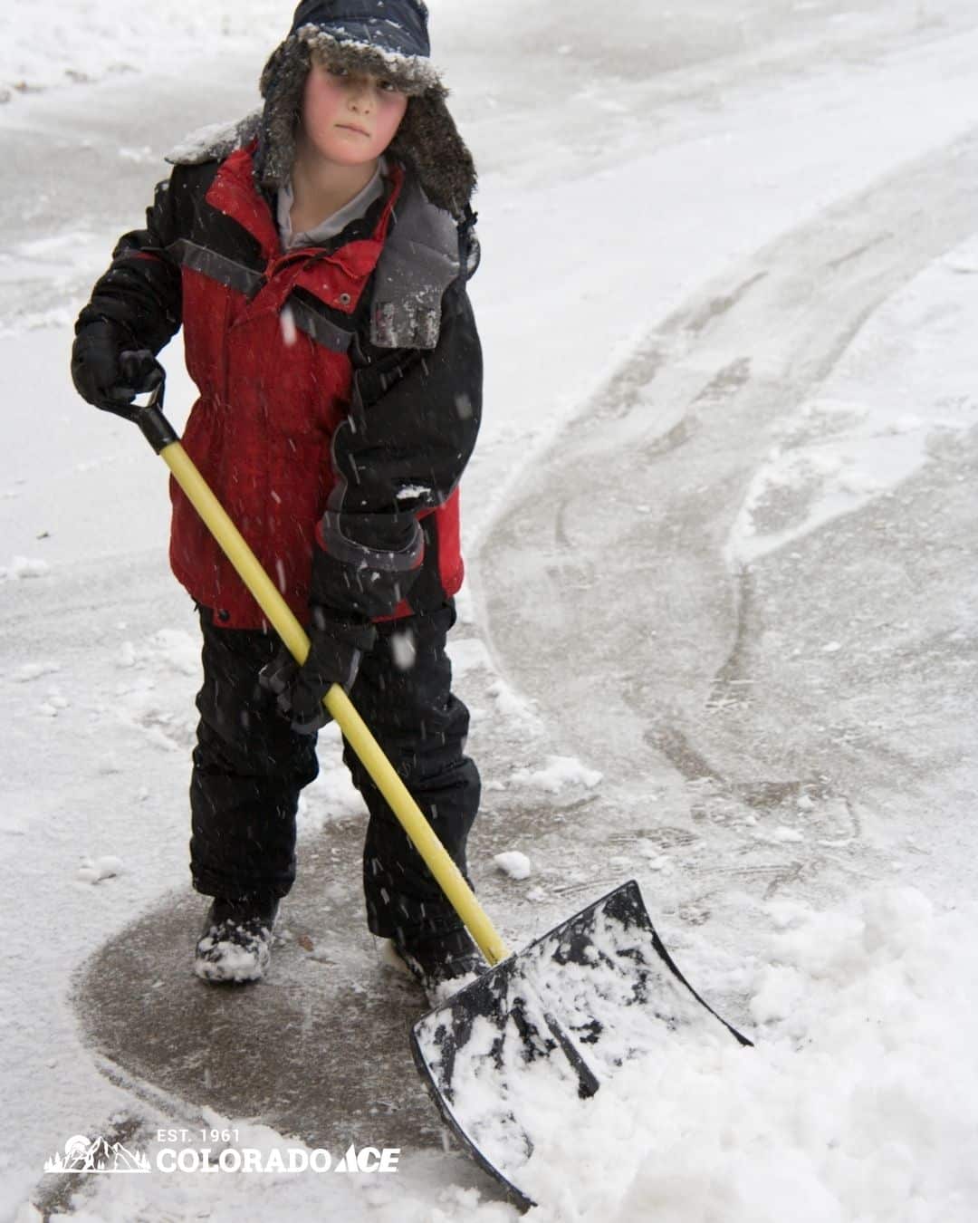 Homeowner using an electric snow blower to clear a snow-covered Colorado driveway